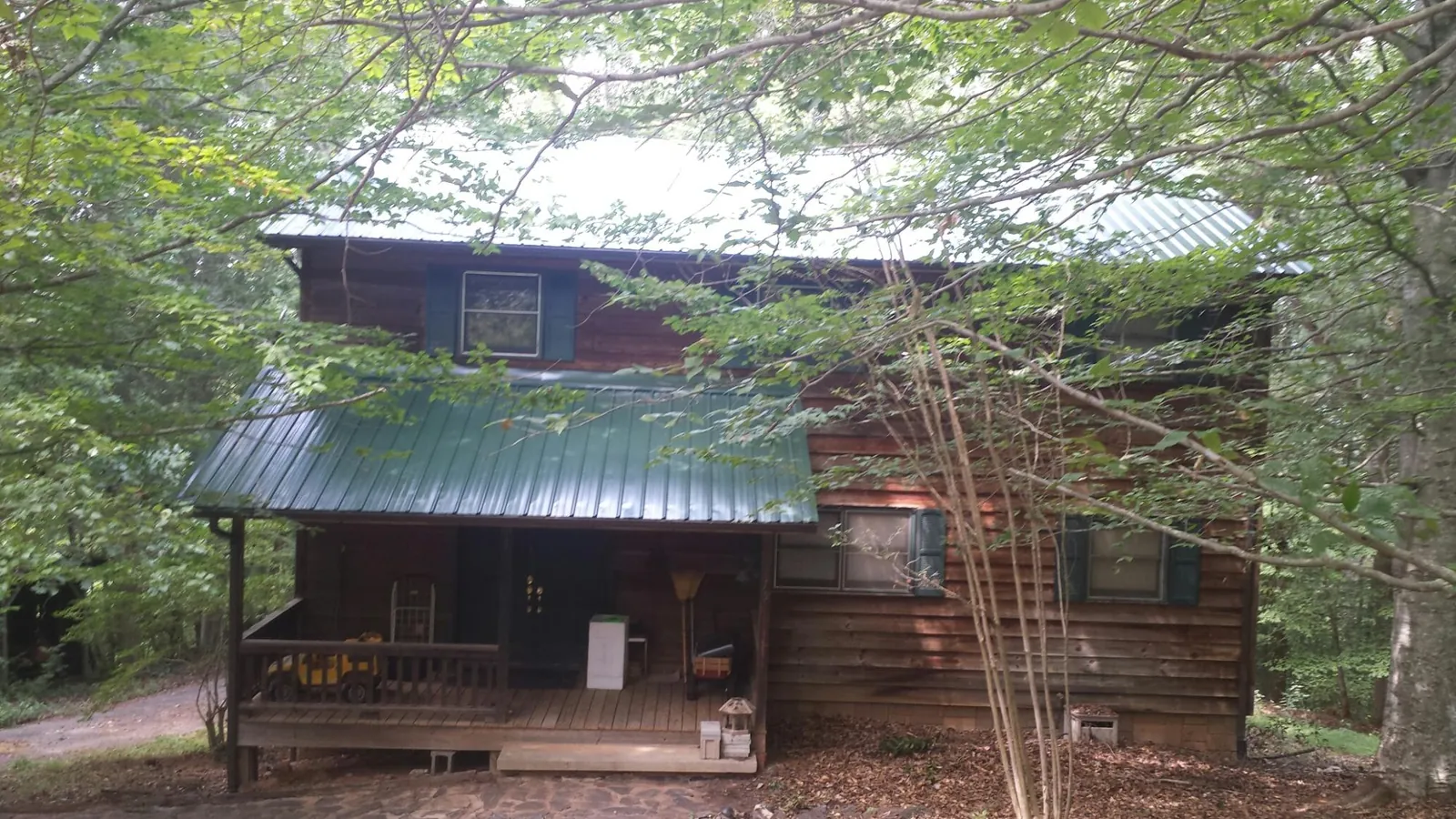 Green metal roof and covered porch on a log cabin in Pala