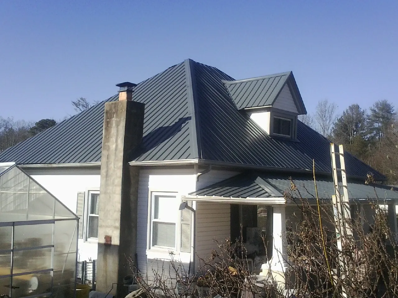 Dark blue standing seam metal roof on a white farmhouse with dormer — Slate & Tile Roof Repair by Roofing Brothers in Pala