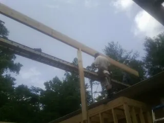Carpenter setting a ridge beam over a new addition frame — Ice Dam Removal by Roofing Brothers in Pala