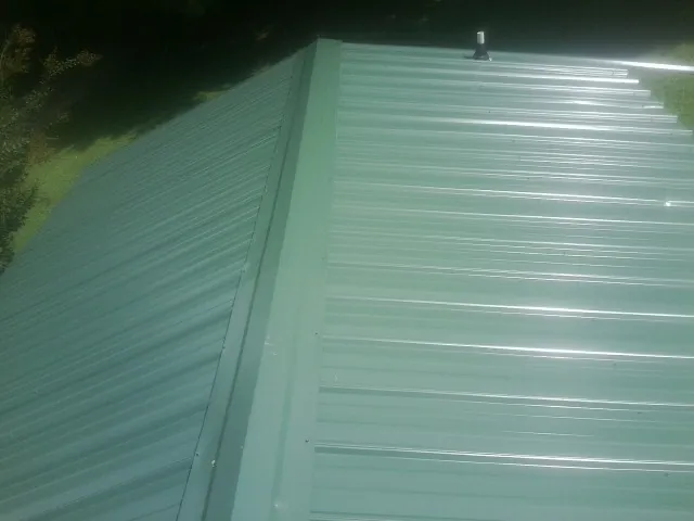 New green metal panels meeting at the ridge of a roof — Flat Roof Repair work by our crew in Pala