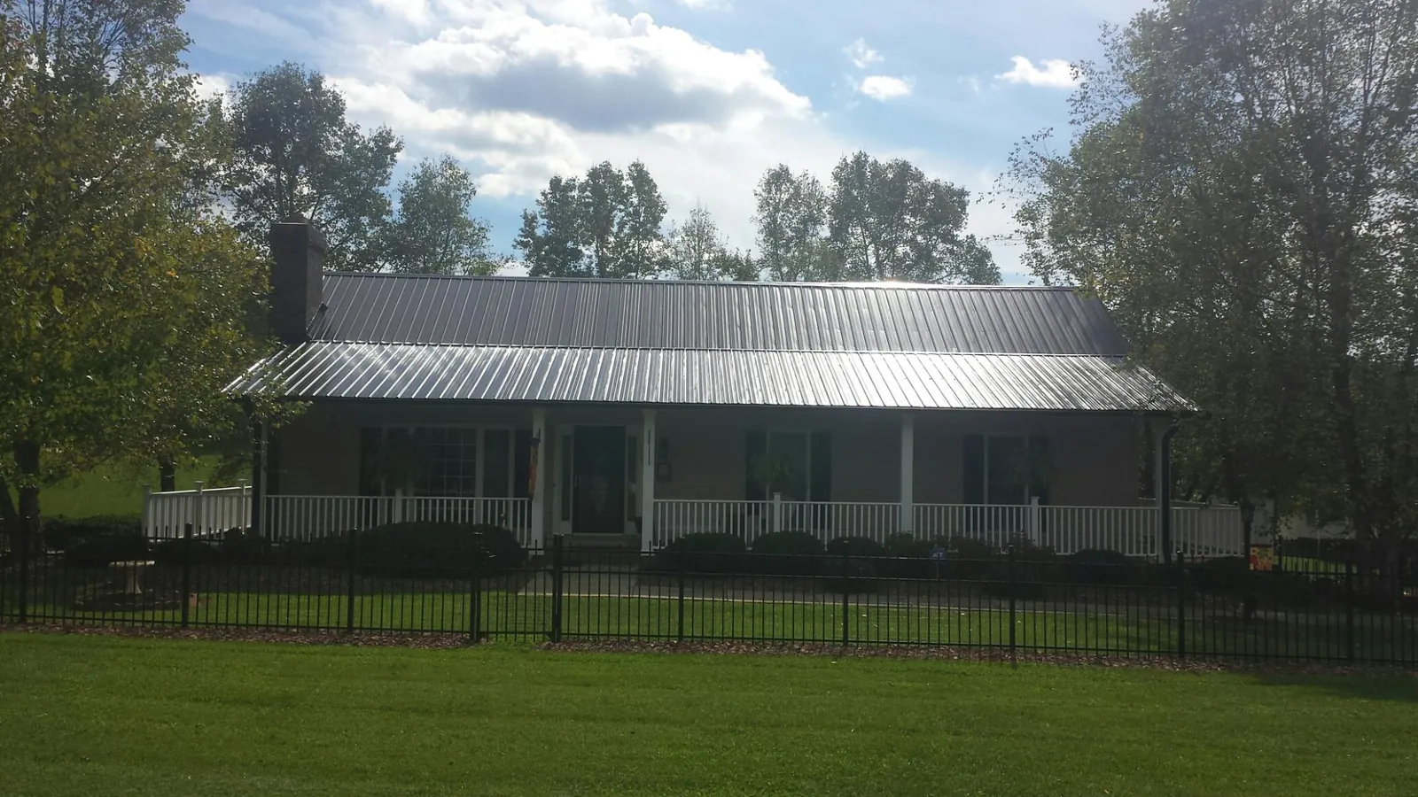 Gray metal roof on a brick ranch with a full width front porch — Gutter Guard Installation work by our crew in Pala
